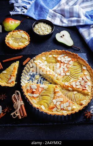 Francese classica Crostata di pere, la Tarte Bourdaloue riempito con pere in camicia e frangipane crema servita su una pietra nera di bordo su un tavolo in cemento, vertic Foto Stock