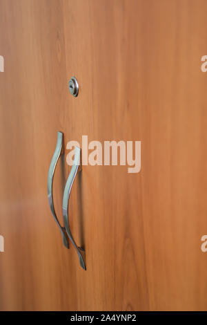 Splendide porte di armadio con serratura e la maniglia della porta in ottone di close-up. Immagine di sfondo di porte in legno di armadietto. Foto Stock