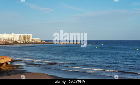 El Medano, Tenerife, Isole Canarie, Spagna - 27 Marzo 2019: vista della spiaggia vulcanica verso il resort hotel, ristoranti e terrazze Foto Stock