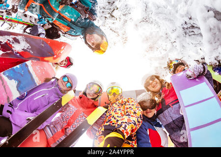 Grande gruppo di amici felici gli sciatori e gli snowboarder si erge nel cerchio e guarda verso il basso. Stazione sciistica Foto Stock