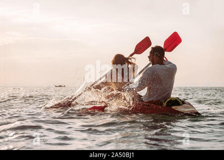 Coppia felice passeggiate in kayak di mare al tramonto Foto Stock