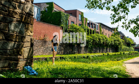 Teen girl in piedi in erba con pantaloncini blu e Blusa nera accanto a Chesapeake e Ohio Canal Foto Stock