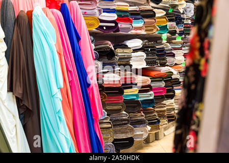 Rotoli di tessuti e prodotti tessili in un negozio della fabbrica. Multi colori e motivi diversi sul mercato di tessuti in rotoli. Foto Stock