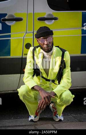 LONDON, Regno Unito - 13 settembre 2019: la gente per strada durante la London Fashion Week. Un uomo in una luce verde tuta e una maglia nera hat pone, lea Foto Stock