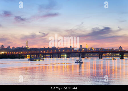 Vista della Madre Patria monumento sopra Dnipro river con Paton bridge e città di Kiev al tramonto, Ucraina Foto Stock