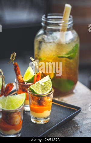 Classic Mojito Cubano con calce, menta e zucchero nero servito in un bicchiere grande e spiedini di gamberi tapas Foto Stock