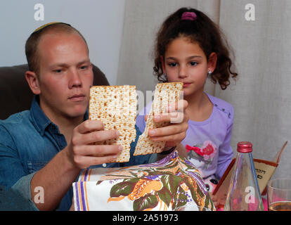 Famiglia ebraica che celebra la Pasqua ebraica.L uomo la benedizione sulla Matzah come essi celebrare il seder. La festa è celebrata la prima notte di Pasqua, vacanze che commemora gli Ebrei esodo dall Egitto. Foto Stock