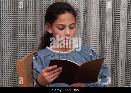 Famiglia ebraica che celebra la Pasqua ebraica.gir legge dall'Haggadah come essi celebrare il seder. La festa è celebrata la prima notte di Pasqua, vacanze che commemora gli Ebrei esodo dall Egitto. Foto Stock