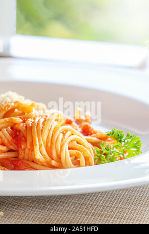 L'immagine verticale di una piastra con gli spaghetti e verdi. il bagliore del sole la prima colazione il cibo fresco all'esterno. In corrispondenza della finestra Foto Stock