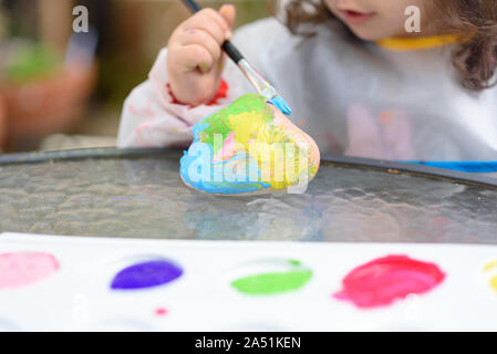 Close-up bambino mani dipinto dal pennello e acquerelli. Ragazzi mano con spazzole disegno su una pietra. Foto Stock