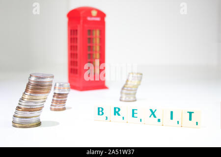 Regno Unito Brexit. Pile di monete con un con la parola 'Brexit' enunciato e una cabina telefonica in background al di fuori della messa a fuoco su uno sfondo bianco. Inghilterra e Foto Stock