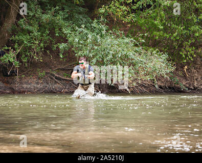 Piena esperienza militare - un giorno commando - in esecuzione attraverso l'acqua con un fucile Kalashnikov AK-47 replica Foto Stock
