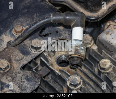 Primo piano della candela di accensione rimossa dal piccolo motore a gas sui tosaerba. Concetto di home procedura dyi manutenzione, messa a punto e la riparazione Foto Stock