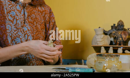 Donna potter rendendo souvenir di ceramica penny whistle nel laboratorio di ceramica Foto Stock