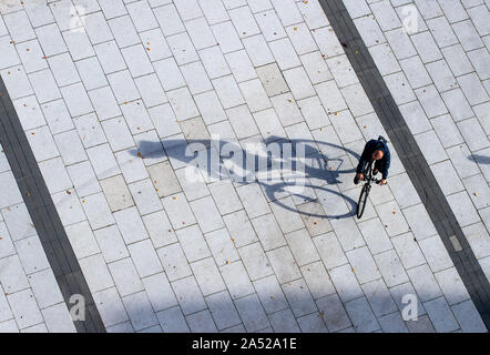 Bautzen, Germania. Xvii oct, 2019. Un uomo che cavalca la sua bicicletta attraverso la piazza di fronte al Reichenturm e getta una lunga ombra. Credito: Jens Büttner/dpa-Zentralbild/dpa/Alamy Live News Foto Stock