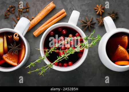 Natale vin brulé bere in tazze con orange citrus,apple,bastoncini di cannella e stelle di anice stellato su grigio scuro dello sfondo concreto vista superiore Foto Stock