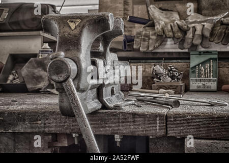 Solida morsa da tavolo su un banco di lavoro disordinati. HDR artistico. Foto Stock