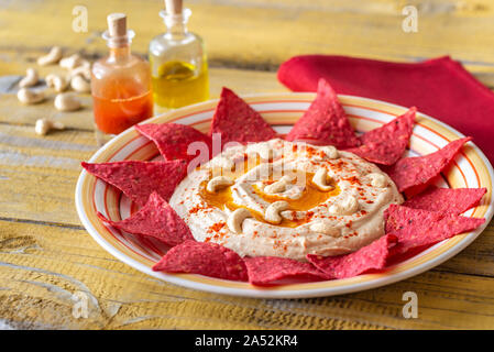 Hummus con tortilla chips sul tavolo di legno Foto Stock