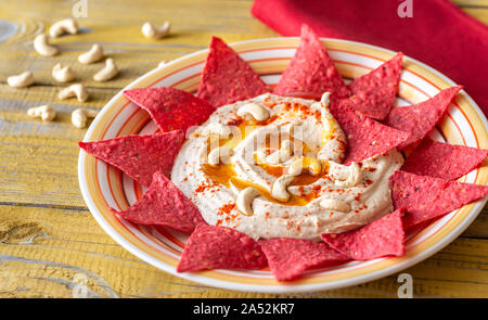 Hummus con tortilla chips sul tavolo di legno Foto Stock