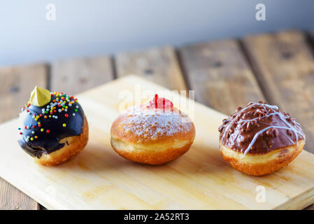 Vista ravvicinata della gustosa varie ciambelle su uno sfondo di legno. Hanukkah celebrazione del concetto. Round jelly o inceppamento sufganiyot ciambella e cioccolato sufganiyah per Chanukah festa ebraica. Foto Stock