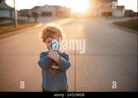 Il Toddler Boy puntando pistola giocattolo fuori in quartiere Foto Stock