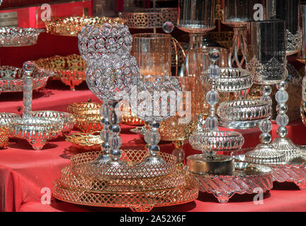 Vetro bicchieri di vino e ciotole con modelli di metallico sul bancone. Diffusione coperchio rosso sul pavimento. Foto Stock