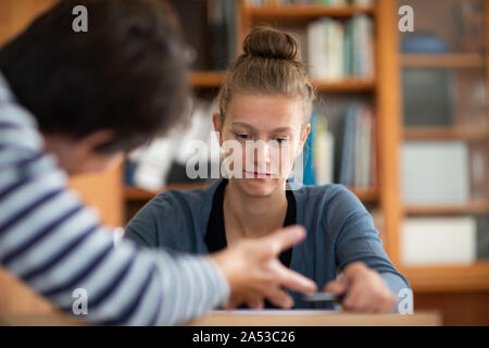 L apprendimento degli studenti in una libreria con l'insegnante Foto Stock