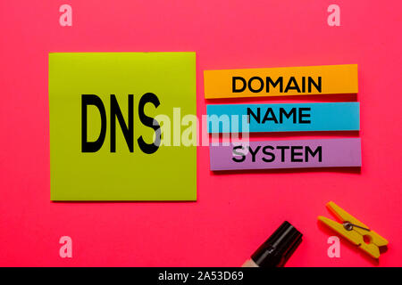 DNS - Domain Name System - acronimo di scrivere su foglietti adesivi isolato su sfondo rosa. Foto Stock