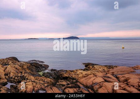 Vista su insels sul fiordo di Oslo, acque calme, cielo nuvoloso. Paesaggio con rocce di colore arancione sulla spiaggia. Costa norvegese in estate. Nesodden Norvegia. Foto Stock