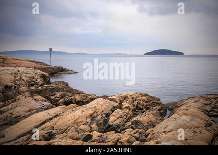 Vista sul fiordo di Oslo, acque calme, visibile l'isola. Paesaggio con rocce sulla spiaggia. Coste norvegesi in estate. Nesodden Norvegia. Nesoddtangen penisola. Foto Stock