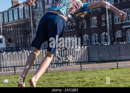 Amsterdam, Olanda, febbraio 25 2019 street flipping boy sul prato del Museumplein di Amsterdam nel suo shorts in una giornata di sole Foto Stock