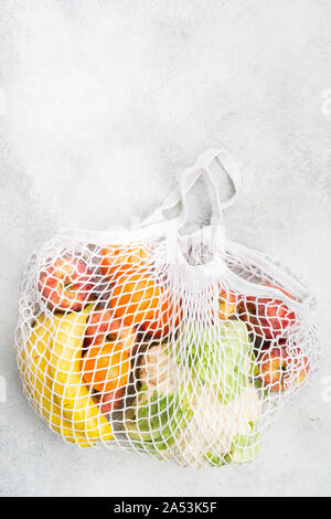 Rifiuti Zero il concetto di shopping, ortaggi frutta in bianco borsa a rete su bianco tavolo da cucina, vista dall'alto, il fuoco selettivo Foto Stock