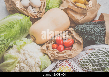 Assortimento di frutta verdura riutilizzabili in maglia bianca, cotone e sacchi di carta bianca sul tavolo da cucina, tonica, vista dall'alto, il fuoco selettivo Foto Stock