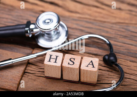 Il sistema HSA Health Conto di risparmio dei blocchi di legno vicino a uno stetoscopio sul tavolo di legno Foto Stock