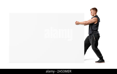 Uomo muscolare tenendo un bianco chiaro display board con i pugni. Foto Stock