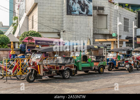 Città di Bangkok, Tailandia - 17 Marzo 2019: parcheggiato gruppo di aprire il colorato triciclo motorizzato taxi in strada. Edificio grigio in retro. Foto Stock