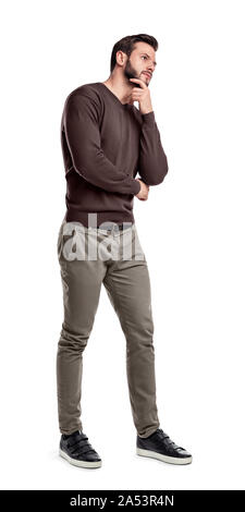 Un uomo barbuto in smart abiti casual sorge in piena altezza con una sola mano toccando il suo mento. Foto Stock