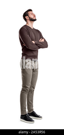 Un uomo barbuto in smart abiti casual sorge in mezzo giro con le braccia incrociate e guarda verso l'alto. Foto Stock