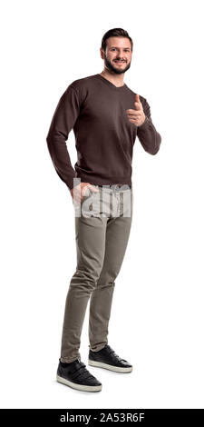 Uomo sorridente in abbigliamento casual appare su uno sfondo bianco e punti con il suo dito indice in telecamera. Foto Stock