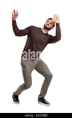 Un uomo barbuto in abito casual sta accovacciata sotto qualcosa di pericoloso al di sopra di lui. Foto Stock