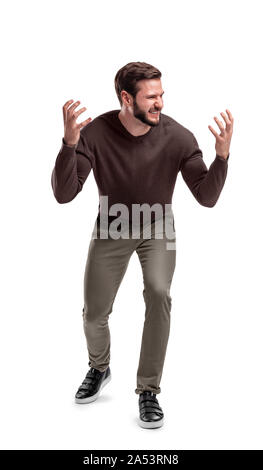 Un aggressivo uomo barbuto in abito casual sorge in semi-bend, mantiene le sue mani vicino alla sua testa e guarda a parte. Foto Stock