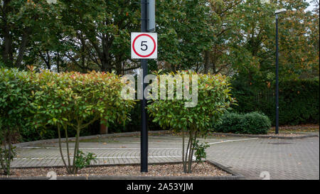 5 MPH segno di velocità in un vuoto di alberata parcheggio su un nuvoloso giorno Foto Stock