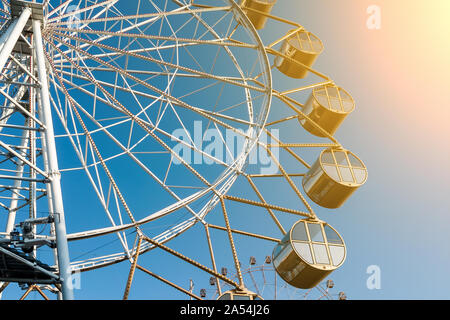 Close-up sulla cabina di una grande ruota panoramica Ferris contro un cielo blu con sole luminoso e brillante nel parco. Il resto e con la famiglia. Foto Stock