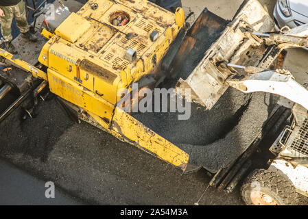 Lavoratori deporre un nuovo rivestimento in asfalto utilizzando bitume caldo. Lavoro di macchinari pesanti e lastricatore. La vista dall'alto Foto Stock