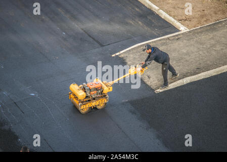 Lavoratori deporre un nuovo rivestimento in asfalto utilizzando bitume caldo. Lavoro di macchinari pesanti e lastricatore. La vista dall'alto Foto Stock