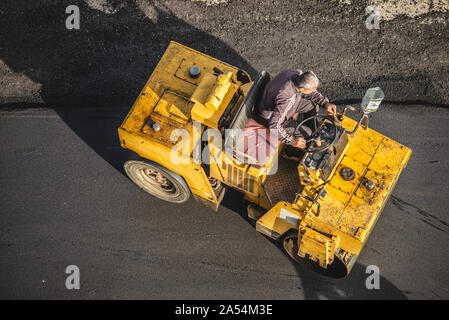 Lavoratori deporre un nuovo rivestimento in asfalto utilizzando bitume caldo. Lavoro di macchinari pesanti e lastricatore. La vista dall'alto Foto Stock