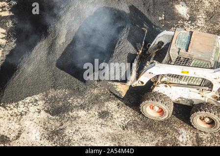 Lavoratori deporre un nuovo rivestimento in asfalto utilizzando bitume caldo. Lavoro di macchinari pesanti e lastricatore. La vista dall'alto Foto Stock