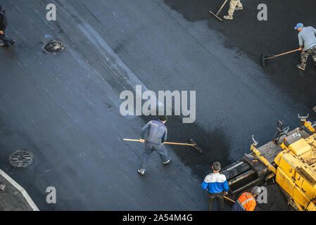 Lavoratori deporre un nuovo rivestimento in asfalto utilizzando bitume caldo. Lavoro di macchinari pesanti e lastricatore. La vista dall'alto Foto Stock