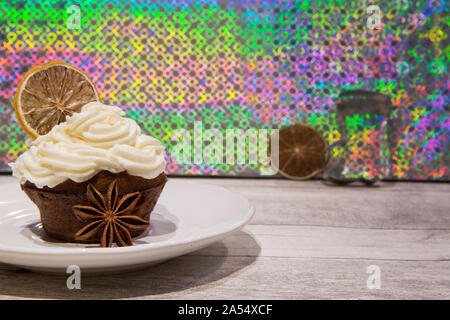 Holiday cupcake con glassa di mascarpone, essiccate di agrumi, arancio, limone e decorazione di calce, cookie cutters e anice stelle. Luminoso dello sfondo colorato. Foto Stock