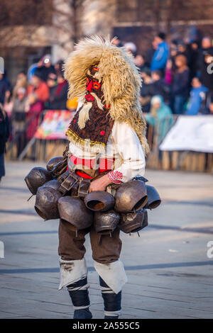 Mummers eseguire rituali per spaventare gli spiriti malvagi a Surva festival di Pernik in Bulgaria. Le persone sono chiamati Kuker. Maschera da lana e big bellls. Foto Stock